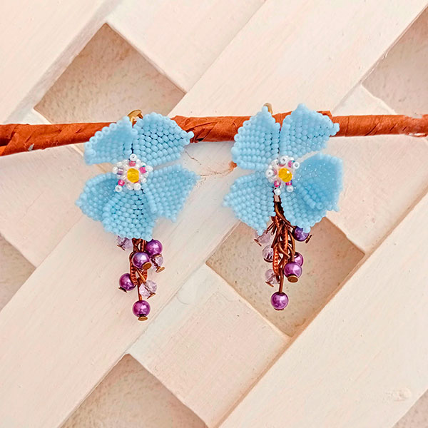 Pendientes artesanales con forma de flor azul, elaborados con cuentas de vidrio y detalles colgantes de perlas