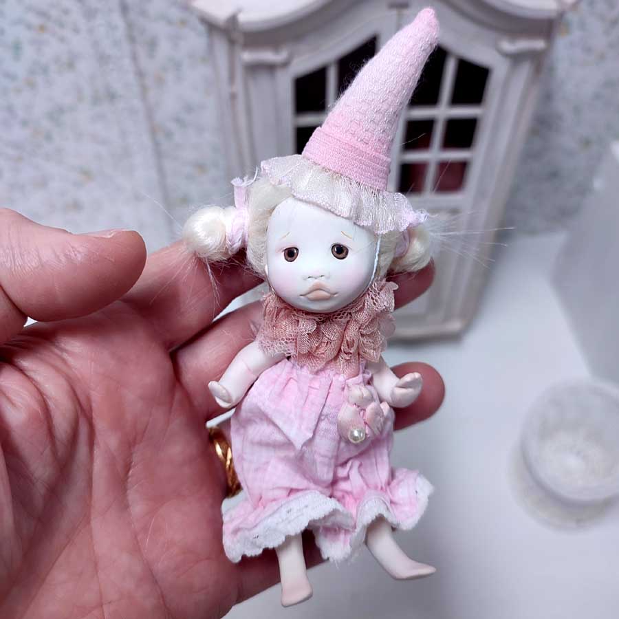 Muñeca pequeña de arcilla y tela vestida de arlequín rosa hecha a mano por Evaninas.