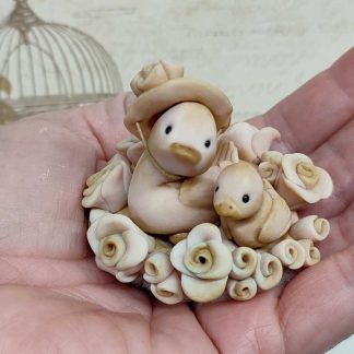 Nido de flores con muñecos con forma de pajaritos modelados en arcilla por Evaninas.