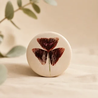 Imán botánico circular de cerámica blanca con ilustración de oxalis triangularis en tono burdeos
